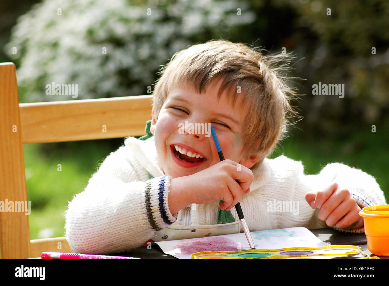Child painting at a table outside Stock Photo - Alamy