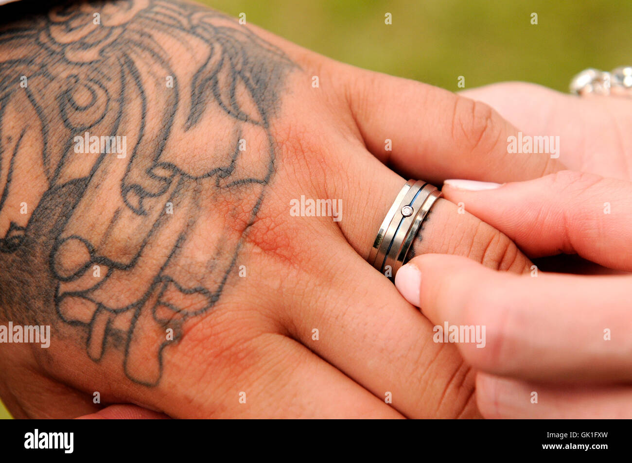 Wedding ring being pushed onto the groom's finger by the bride. Outdoor wedding ceremony. Stock Photo