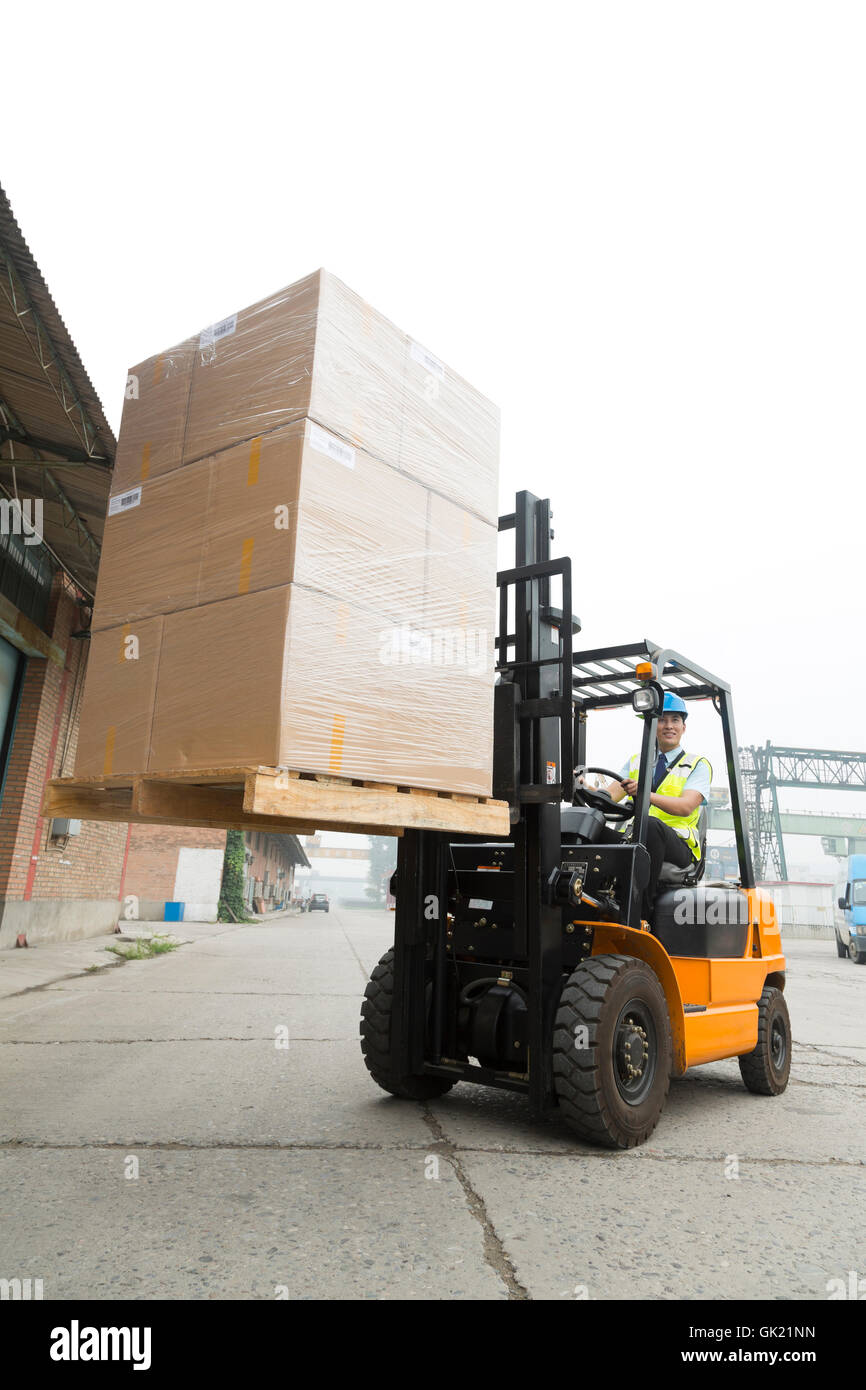 Warehouse worker driving forklift loading and unloading cargo Stock ...