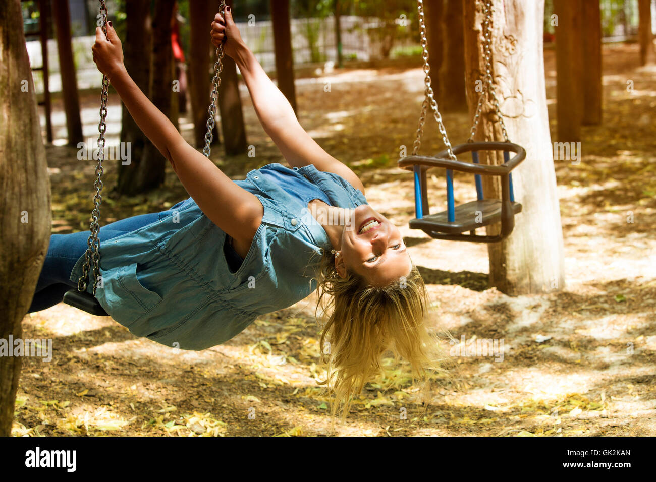blond woman sitting carefree and happy on a swing Stock Photo