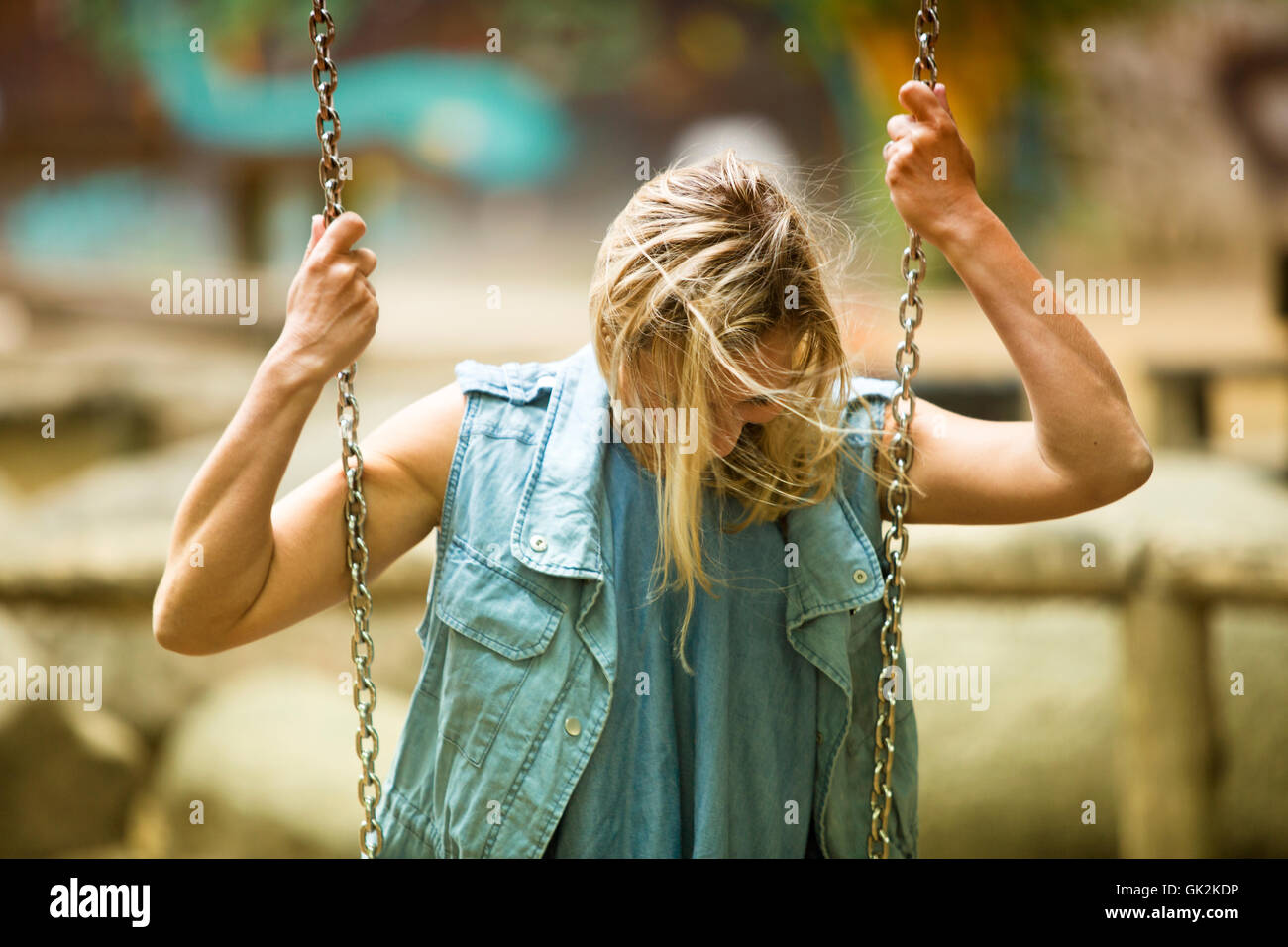 blond woman sitting on swing at playground having fun Stock Photo