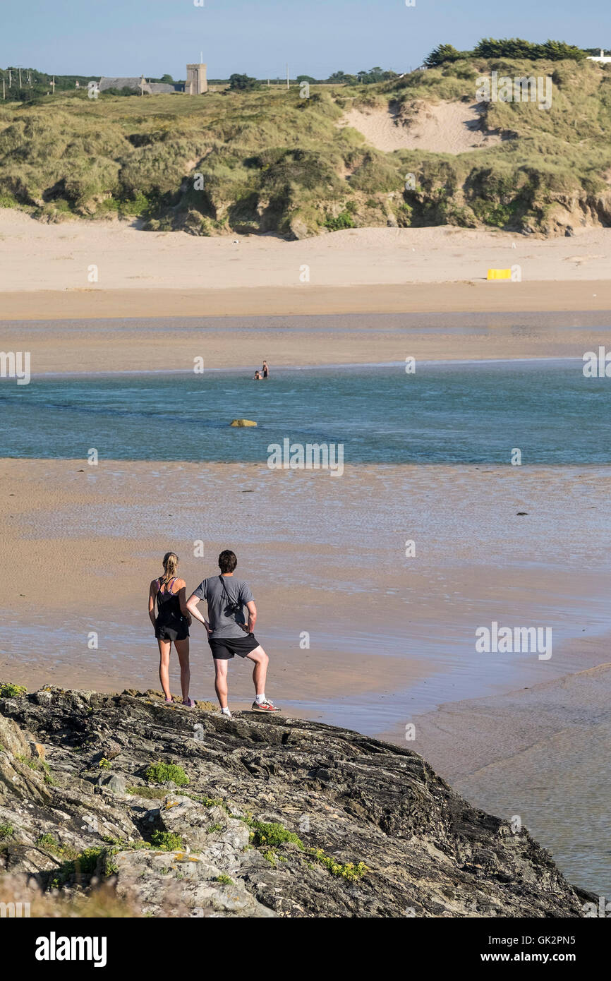 Two people stand on East Pentire and look out over Crantock Beach in Newquay, Cornwall. Stock Photo