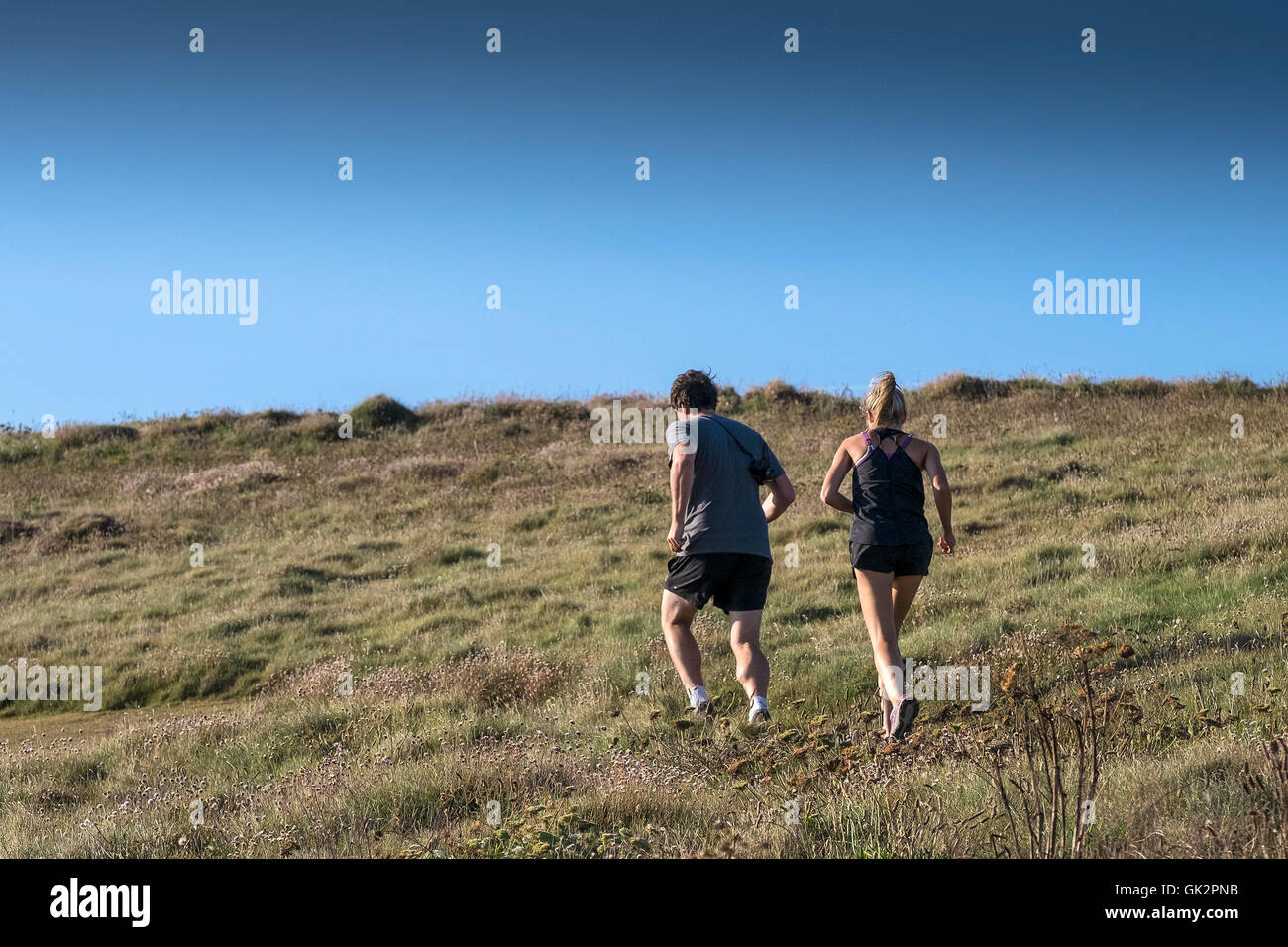 People running on East Pentire in Newquay, Cornwall. Stock Photo