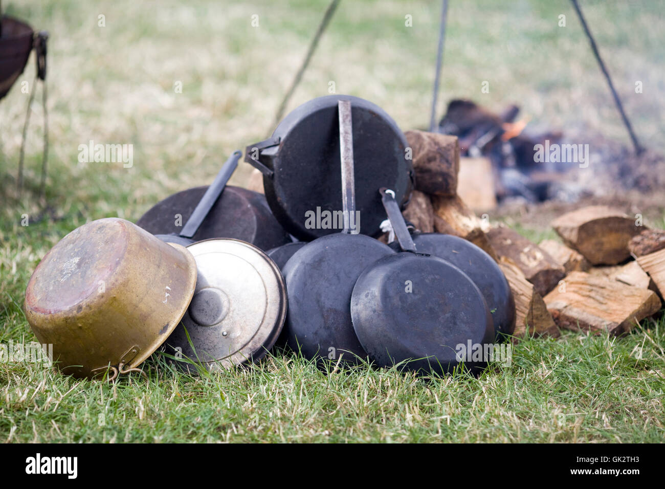 old frying pans and saucepans near an open wood fire Stock Photo