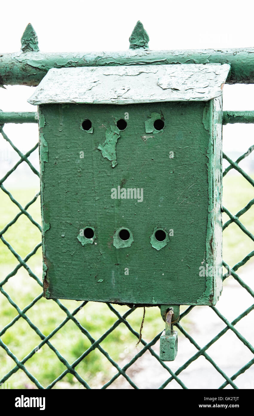 Old green metallic mailbox on the fence. Mail delivery. Retro object. Vertical composition. Stock Photo