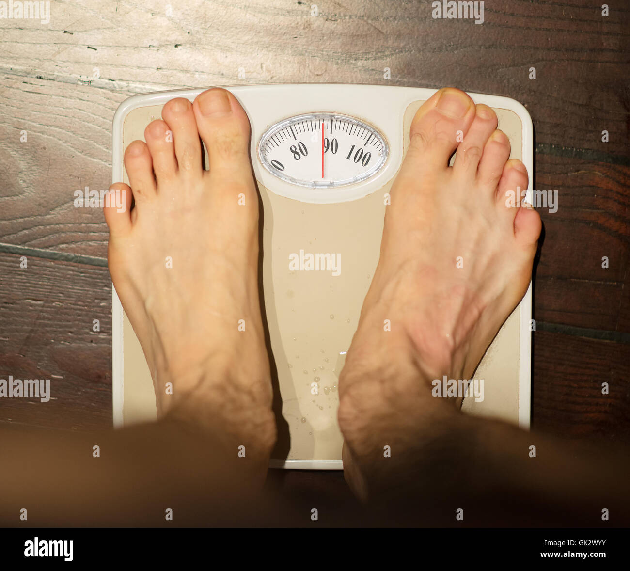 Man standing on scales in bathroom. About 90 kg Stock Photo - Alamy