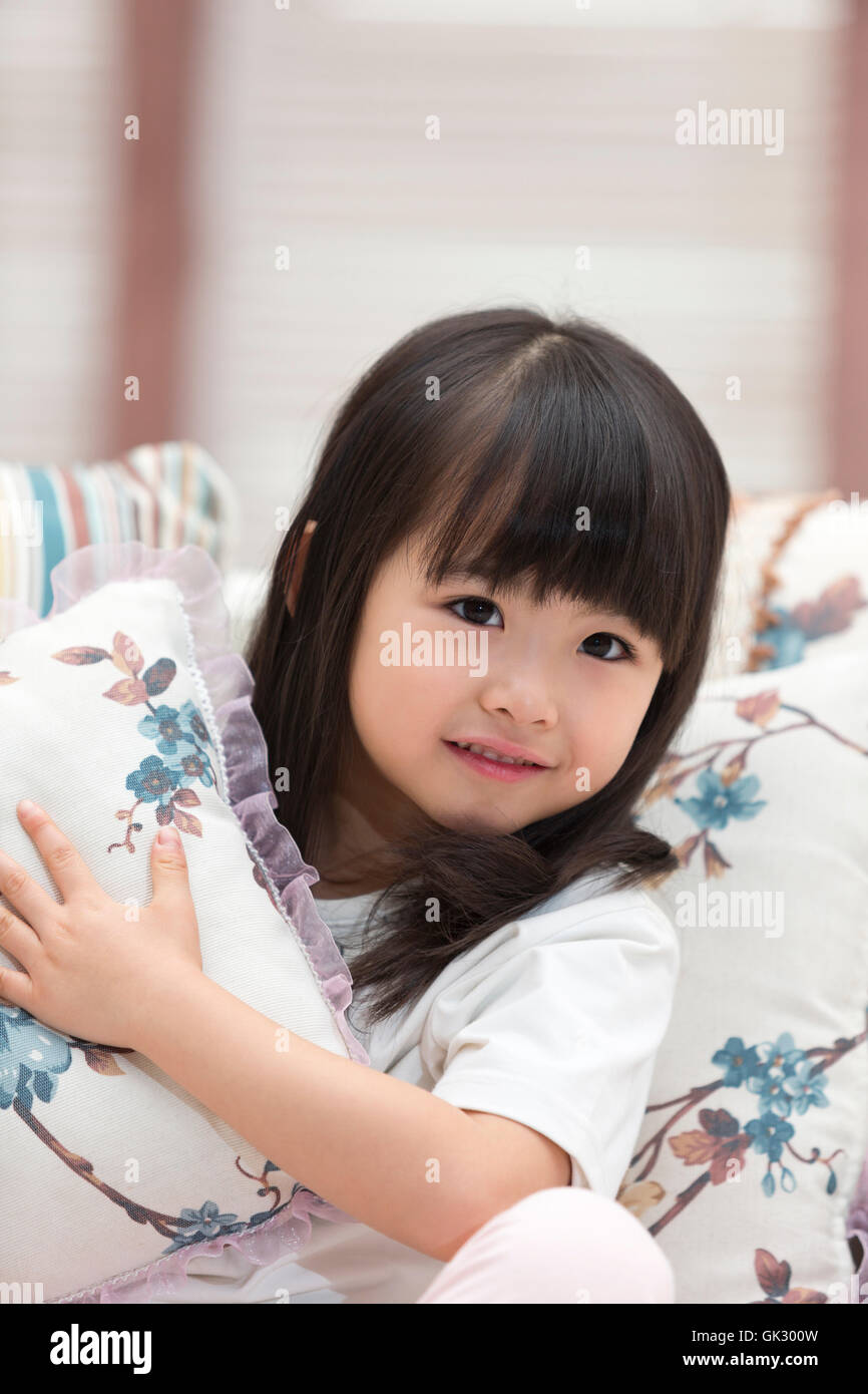 Happy little girl sitting on the couch Stock Photo - Alamy