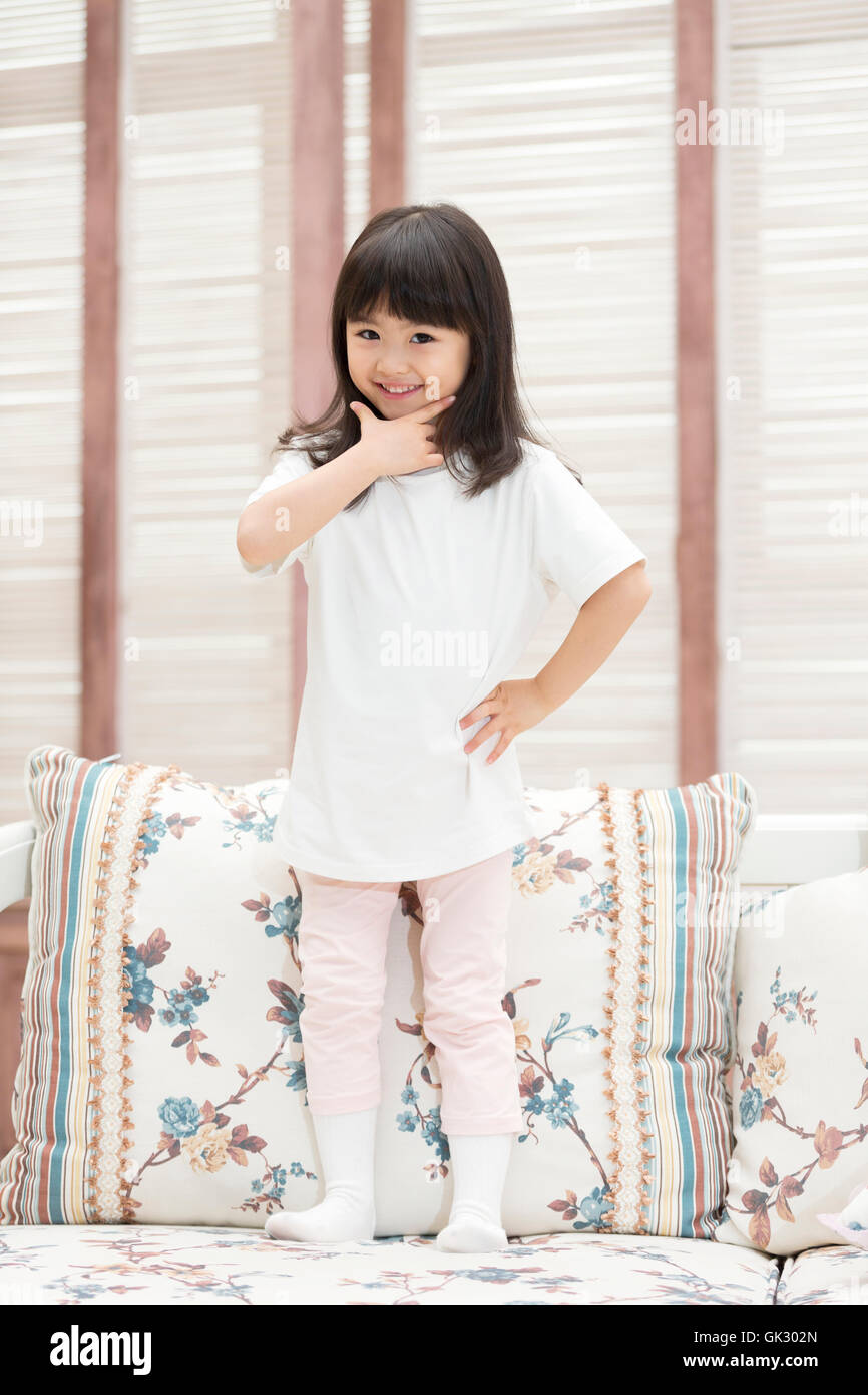 Happy little girl sitting on the couch Stock Photo - Alamy