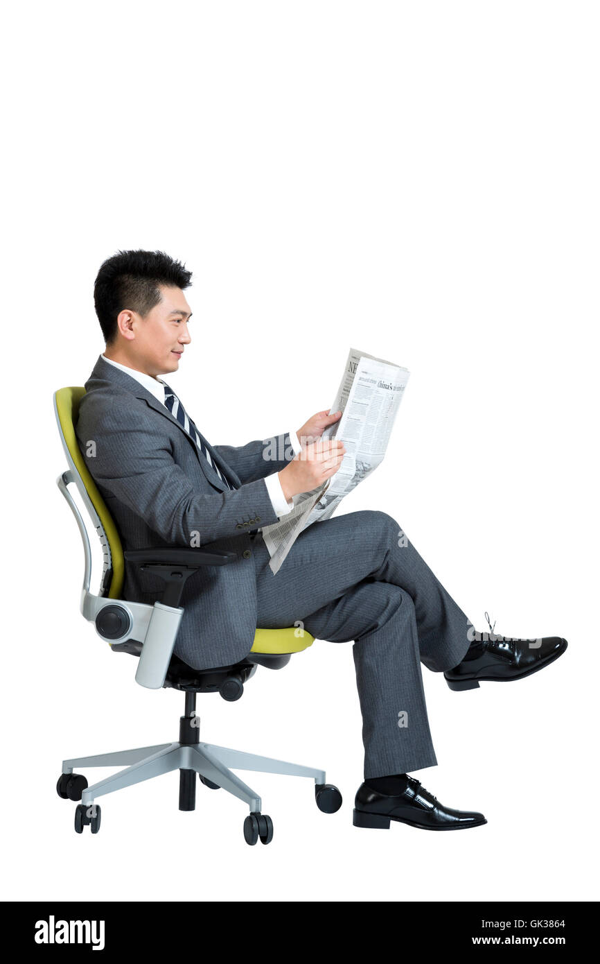 Studio shot business man reading the newspaper sitting on office chair ...