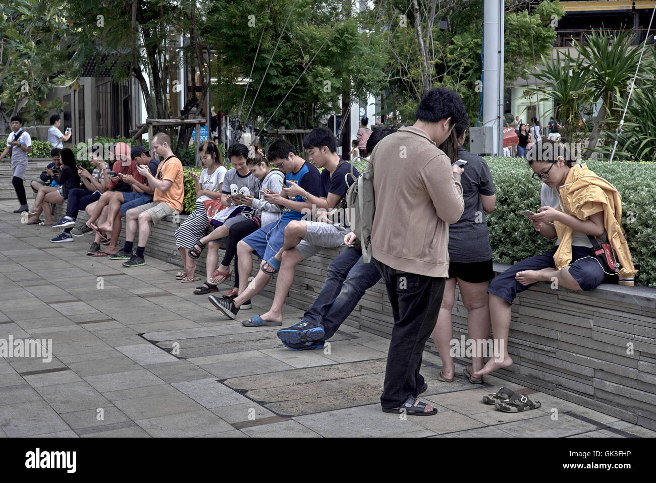 Concept. Non-verbal communication of speechless humans. Line of people engrossed in the fixation of mobile phone communication. Stock Photo