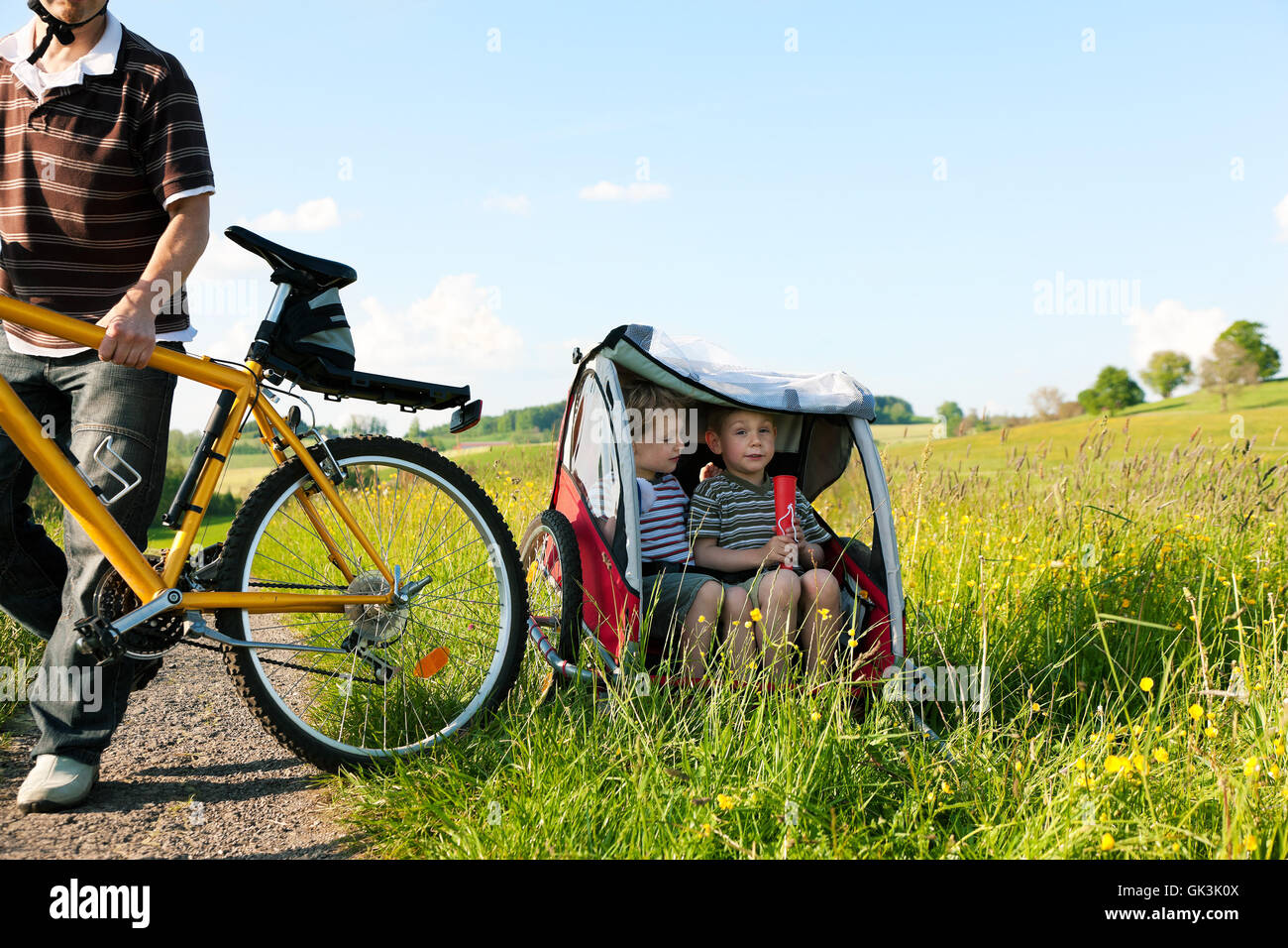 family rides a bike in the summer with trailer Stock Photo