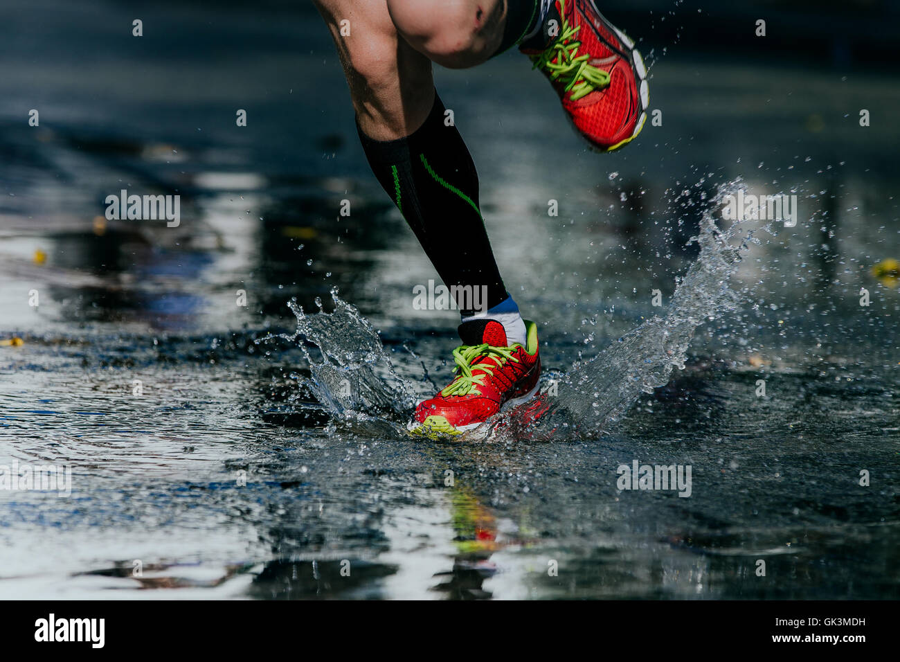 water splashes from under its running shoes men athlete running marathon Stock Photo