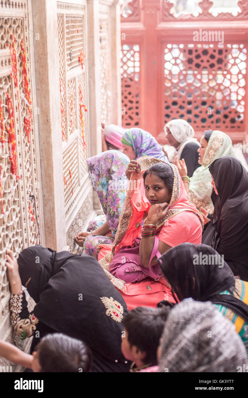 A women adjusts her dress as she prays at a muslim temple in Nizamuddin in Delhi, India.  Credit: Euan Cherry Stock Photo