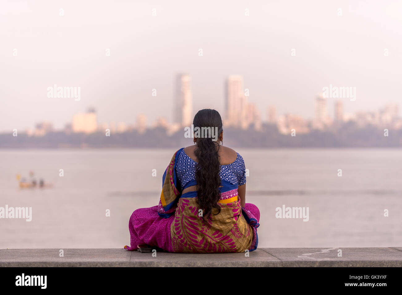 An Indian women looks over the bay, which has fishing boats working in Mumbai India  Credit: Euan Cherry Stock Photo