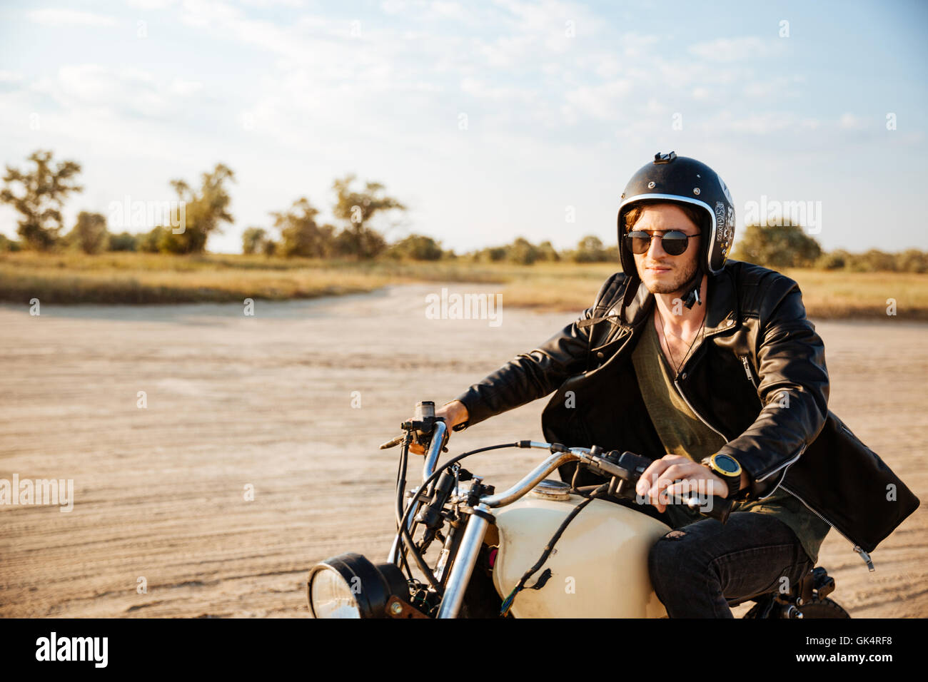 Young brutal man in a black jacket and glasses driving retro motorcycle  Stock Photo - Alamy