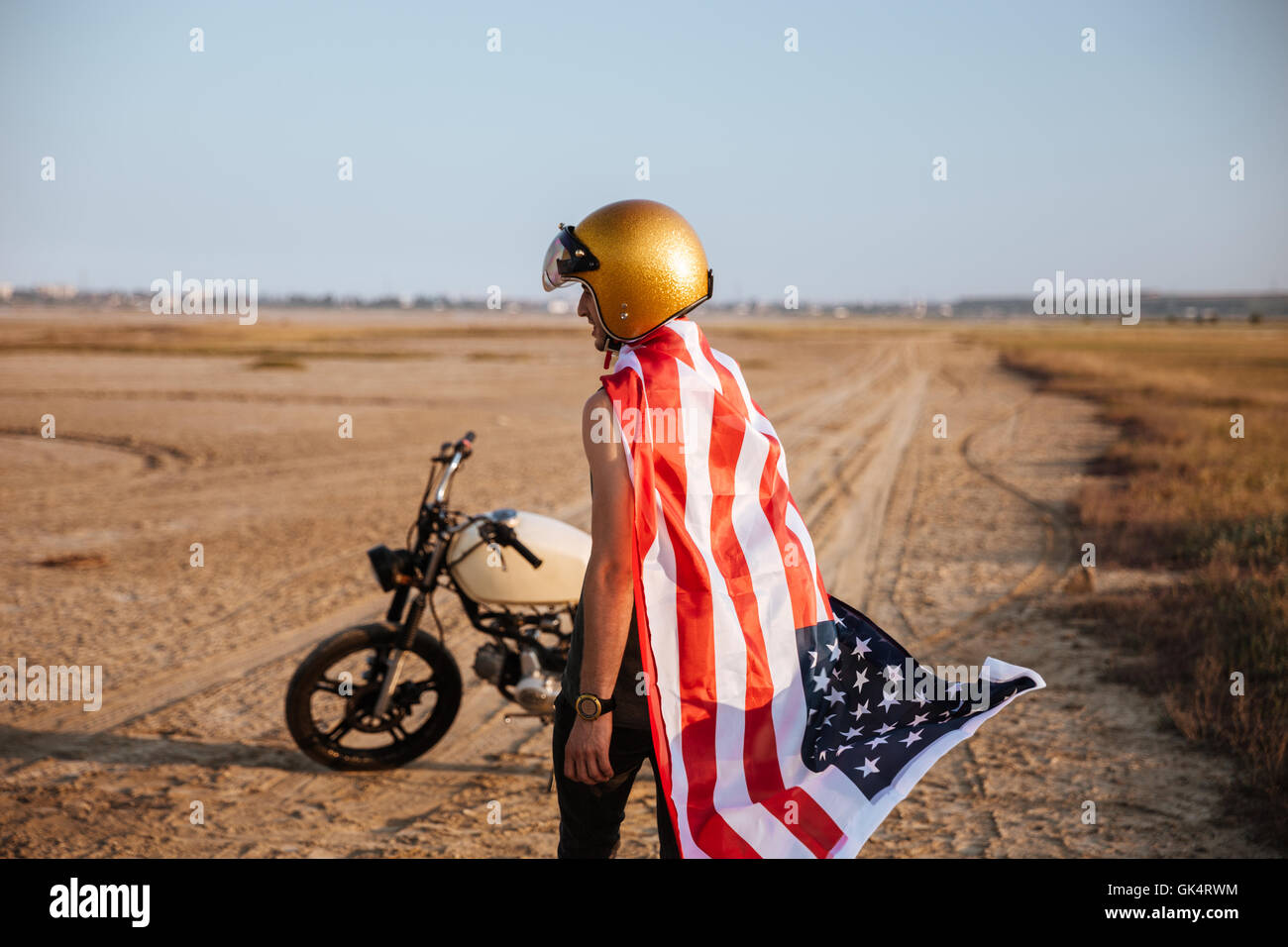 Young brutal man wearing american flag cape and golden helmet standing
