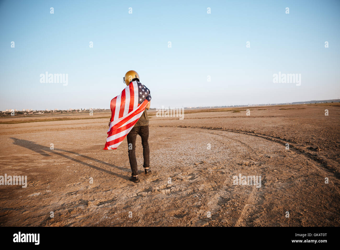 Young brutal man wearing american flag cape and golden helmet walking