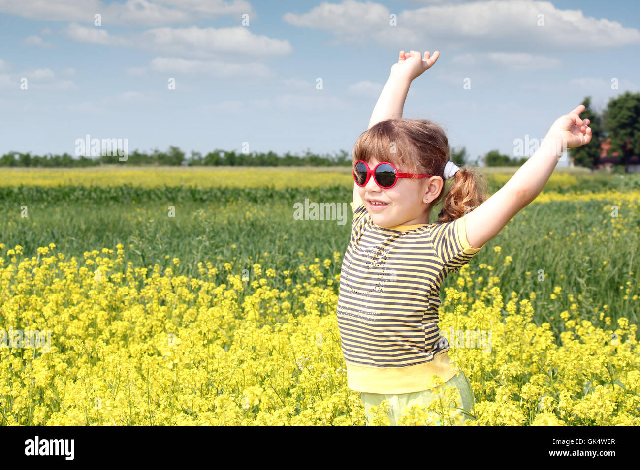 happy little girl standing in yellow flower field Stock Photo - Alamy