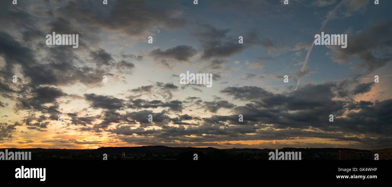 panorama of the sky during sunset or sunrise with cumulus clouds colored orange by the sun. Stock Photo