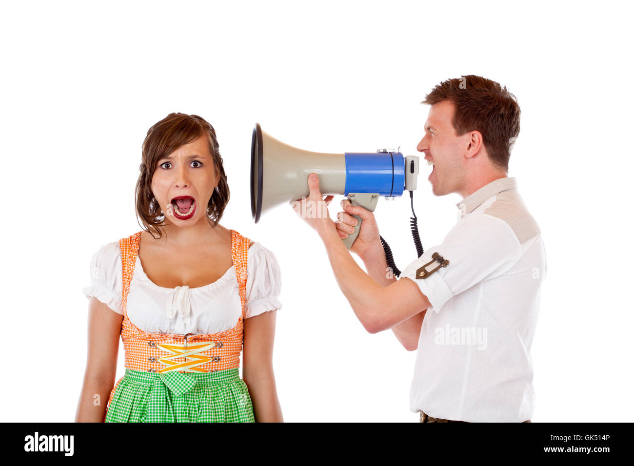 man yells woman in dirndl with megaphone loud ear Stock Photo