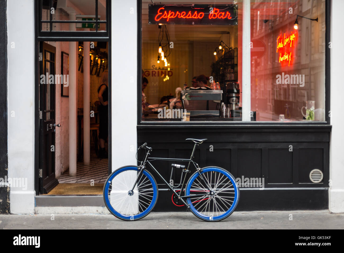 A bicycle with blue wheels is leaning outside a coffee bar in Londons Soho district Stock Photo