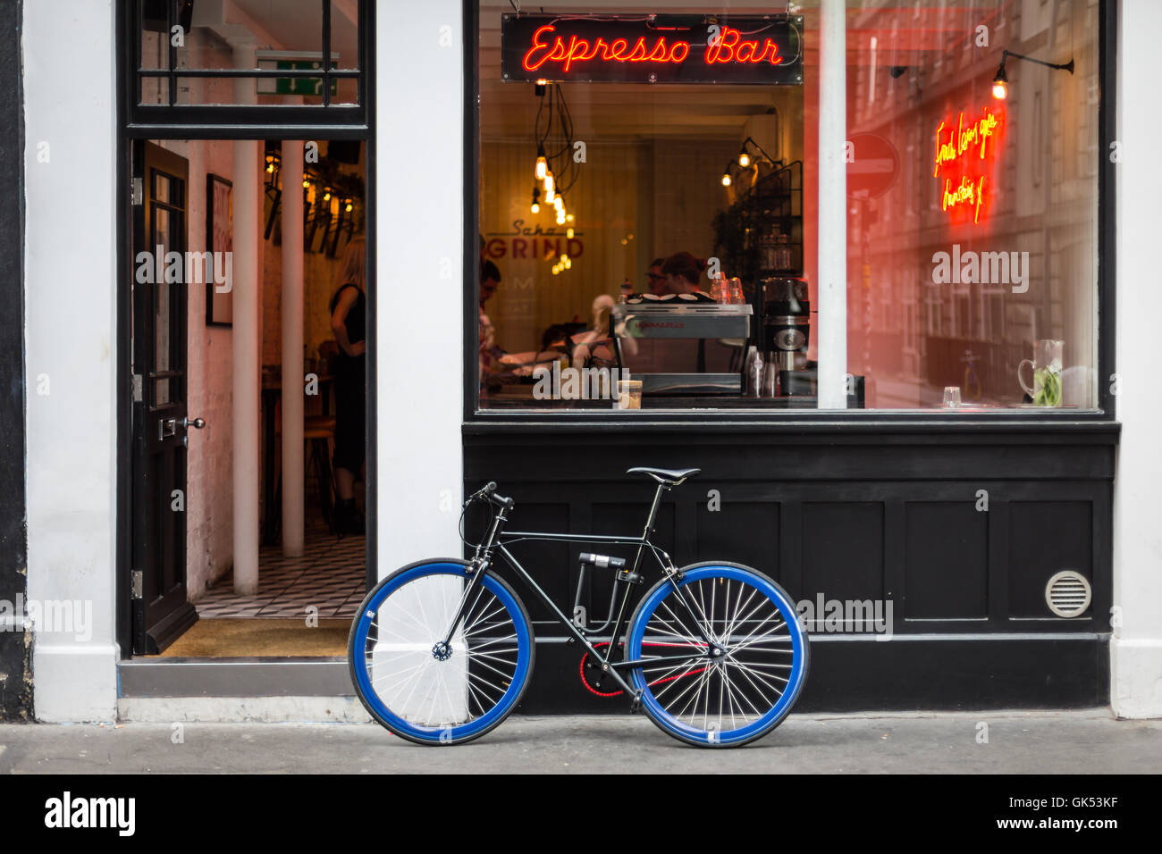 A Bicycle With Blue Wheels Is Leaning Outside A Coffee Bar In