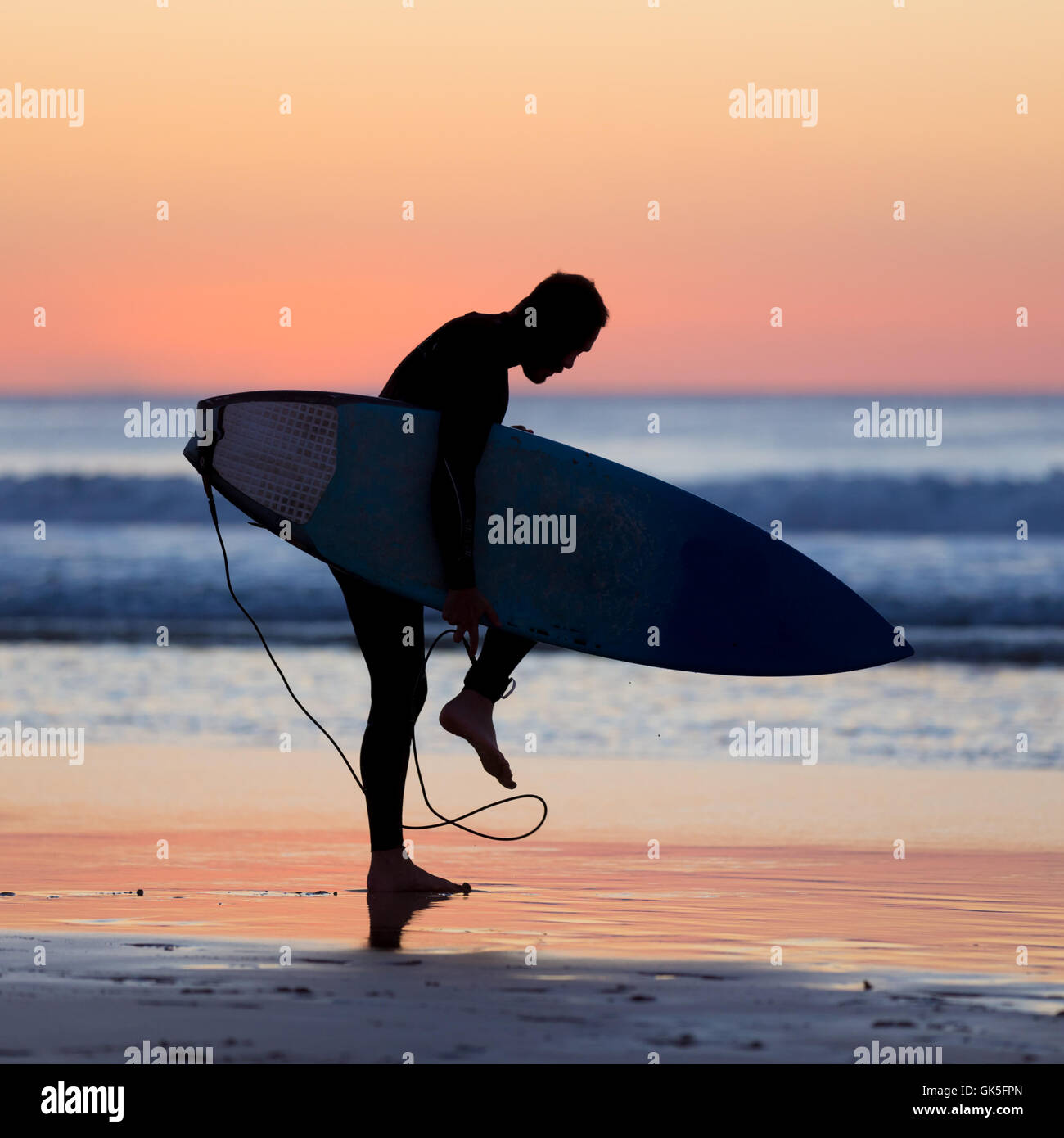 Silhouette of male surfer on the beach with the surfboard in sunset ...