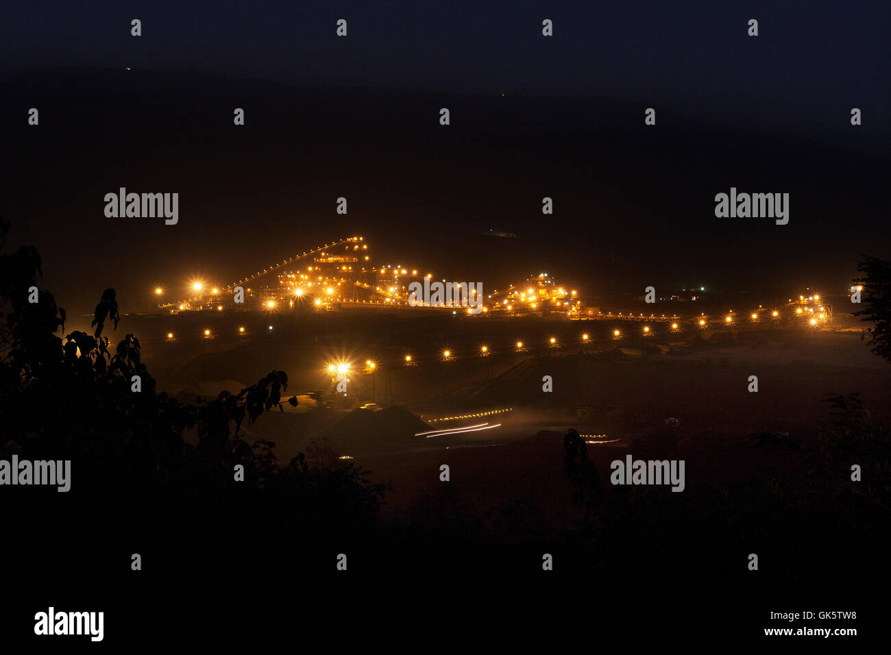 Mining operations for transporting and managing iron ore. Wide view at night new mine processing plant lit up and illuminated.  West Africa. Stock Photo