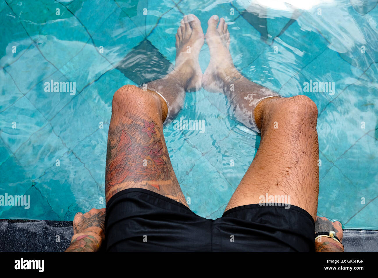 Mans leg with tattoos on the side of a swimming pool Stock Photo Alamy
