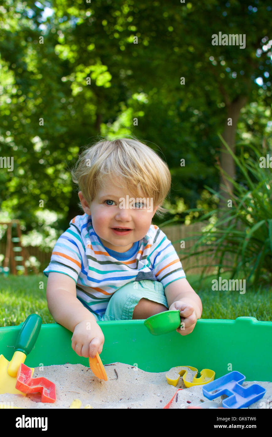 young happy toddler boy smiling and playing in sandbox Stock Photo