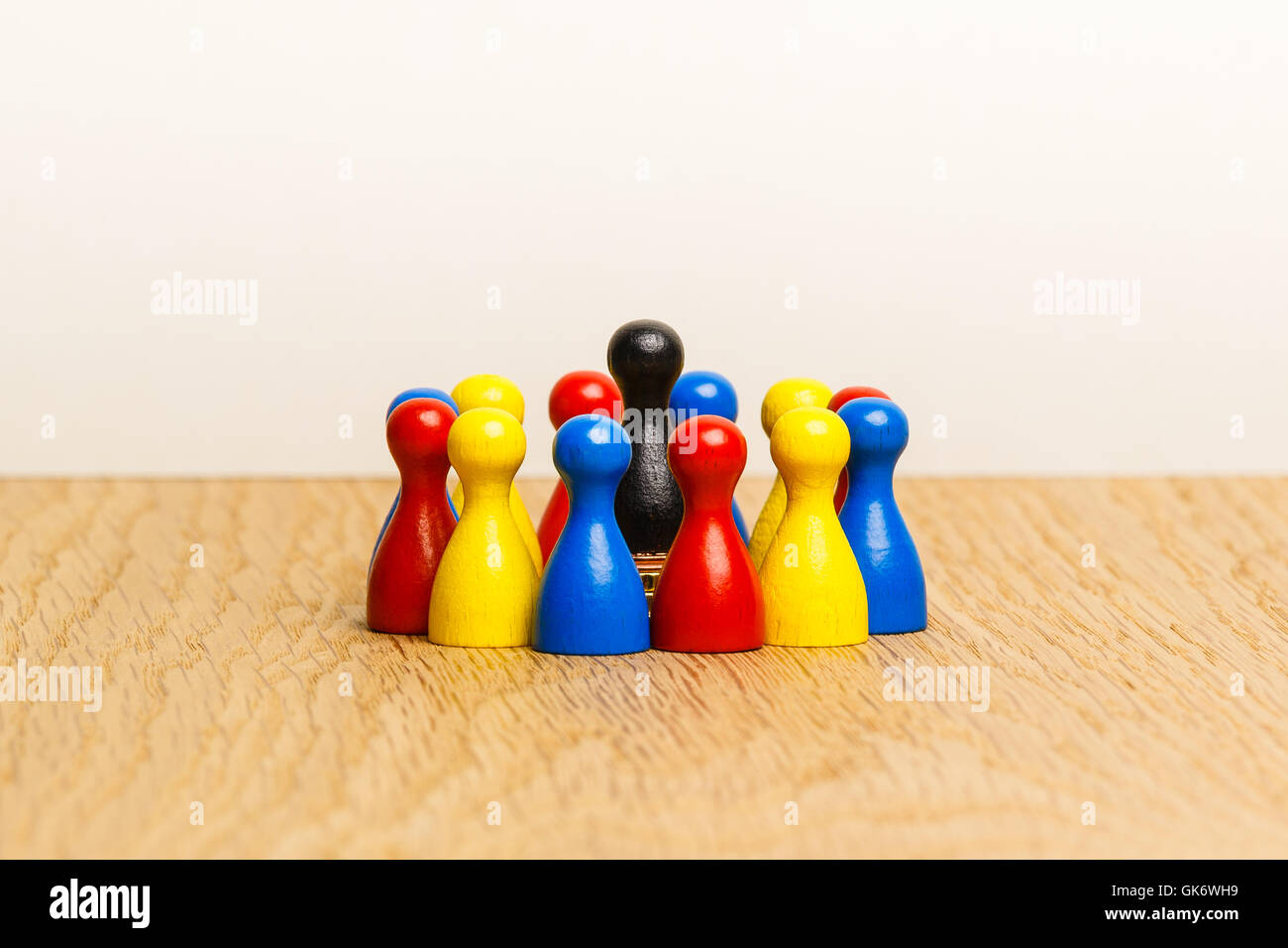 Concept: leader, leadership and adoration with a circle of pawn figures. With black pawn in center and colorful pawn figures aro Stock Photo