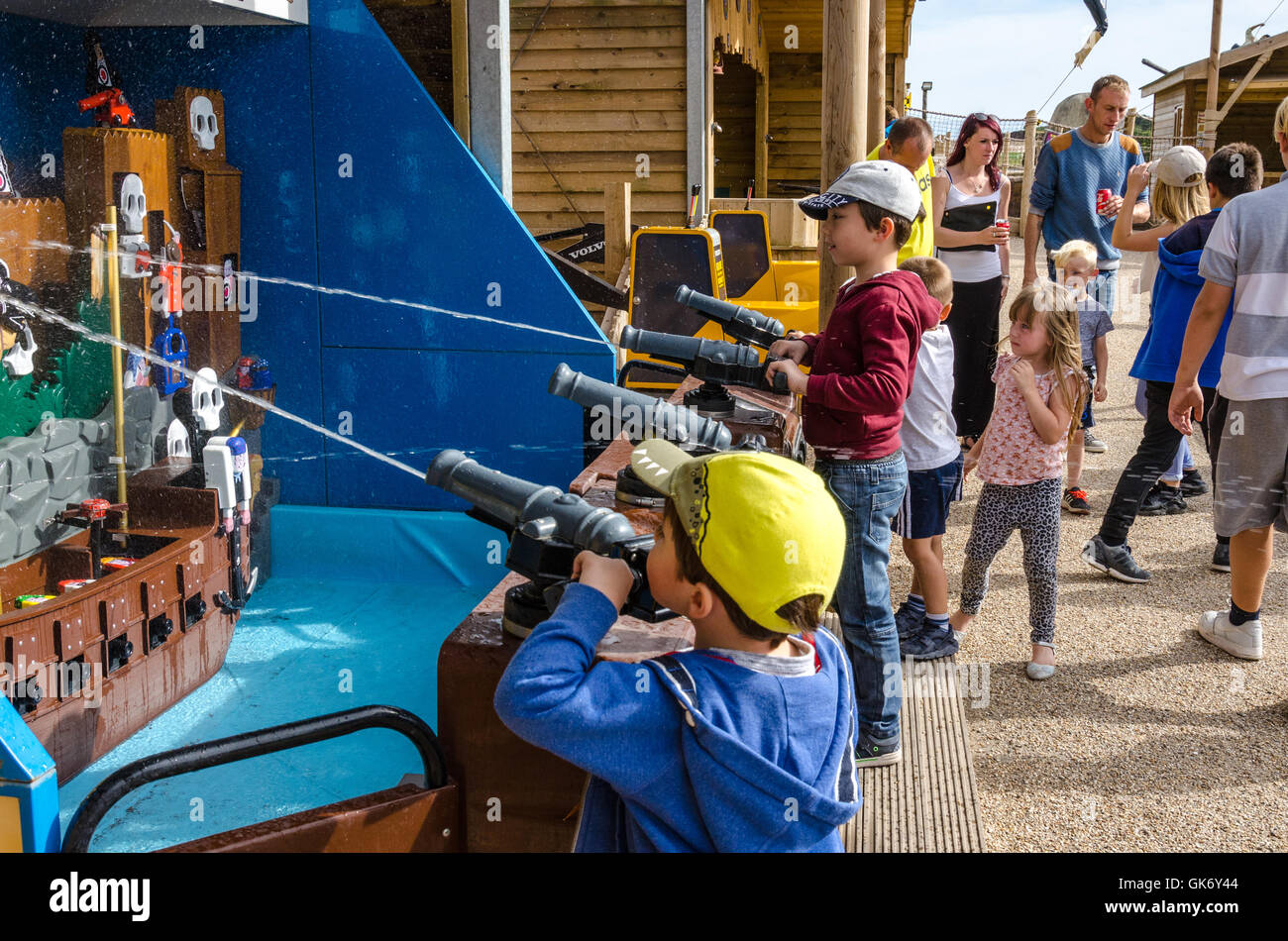 A couple of young brothers play on a water cannon shooting game at the fairground Stock Photo