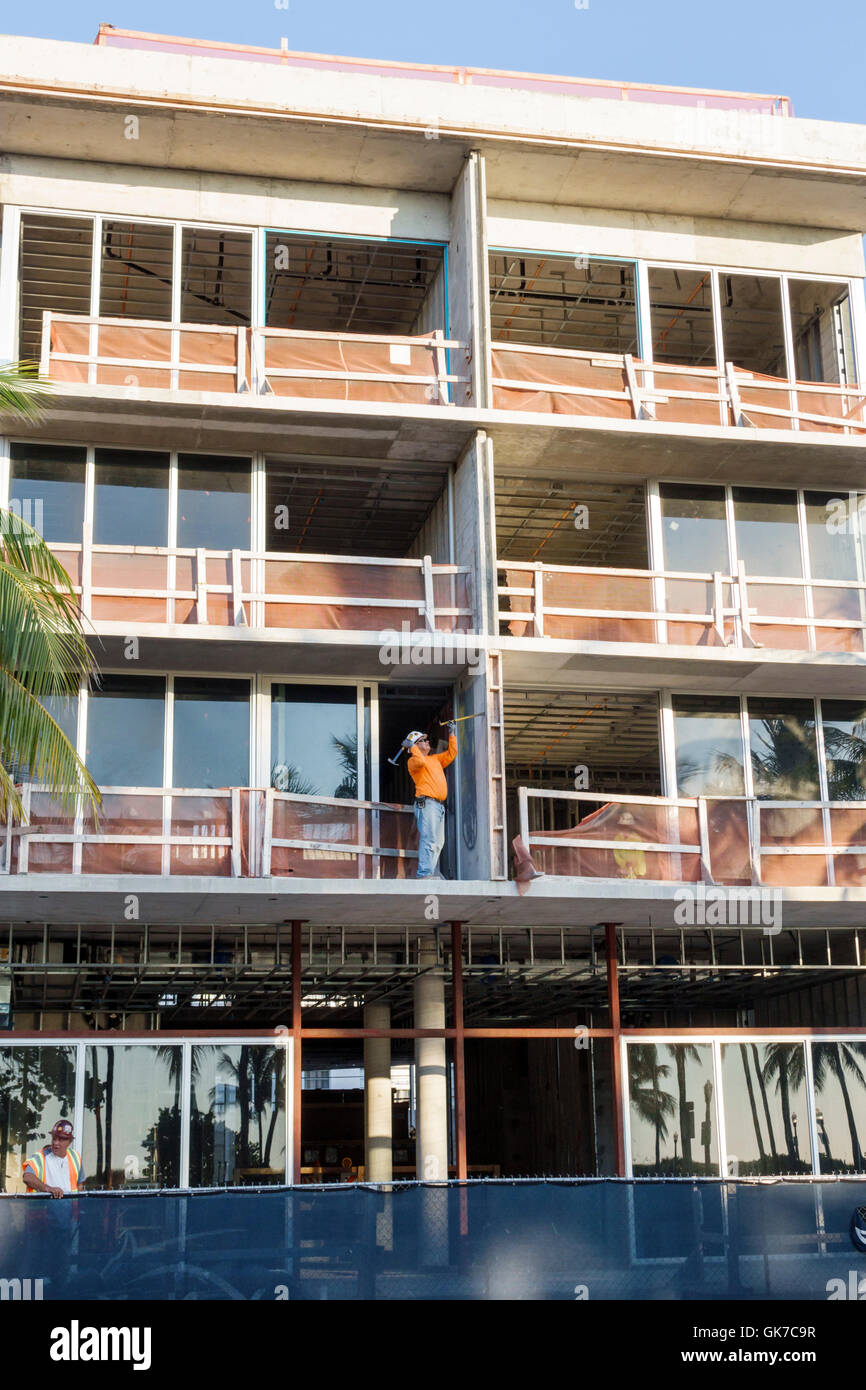 Miami Beach Florida,South Beach,building,multi-story,new construction,adult,adults,man men male,worker,laborer,job,balcony,hammering,fence,al safety,g Stock Photo