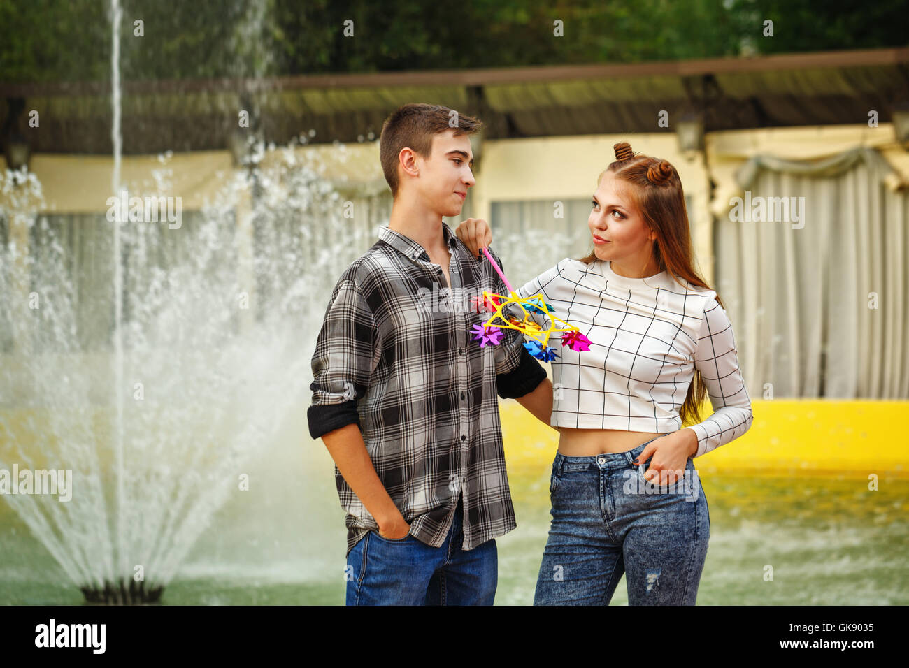 Enamoured teenagers. Girlfriend and boyfriend strolling in a city park.  Girl holds in the hands of the pinwheel Stock Photo - Alamy