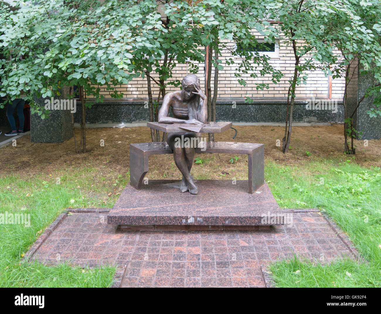 Bronze sculpture of a student sitting at his desk, in patio of the