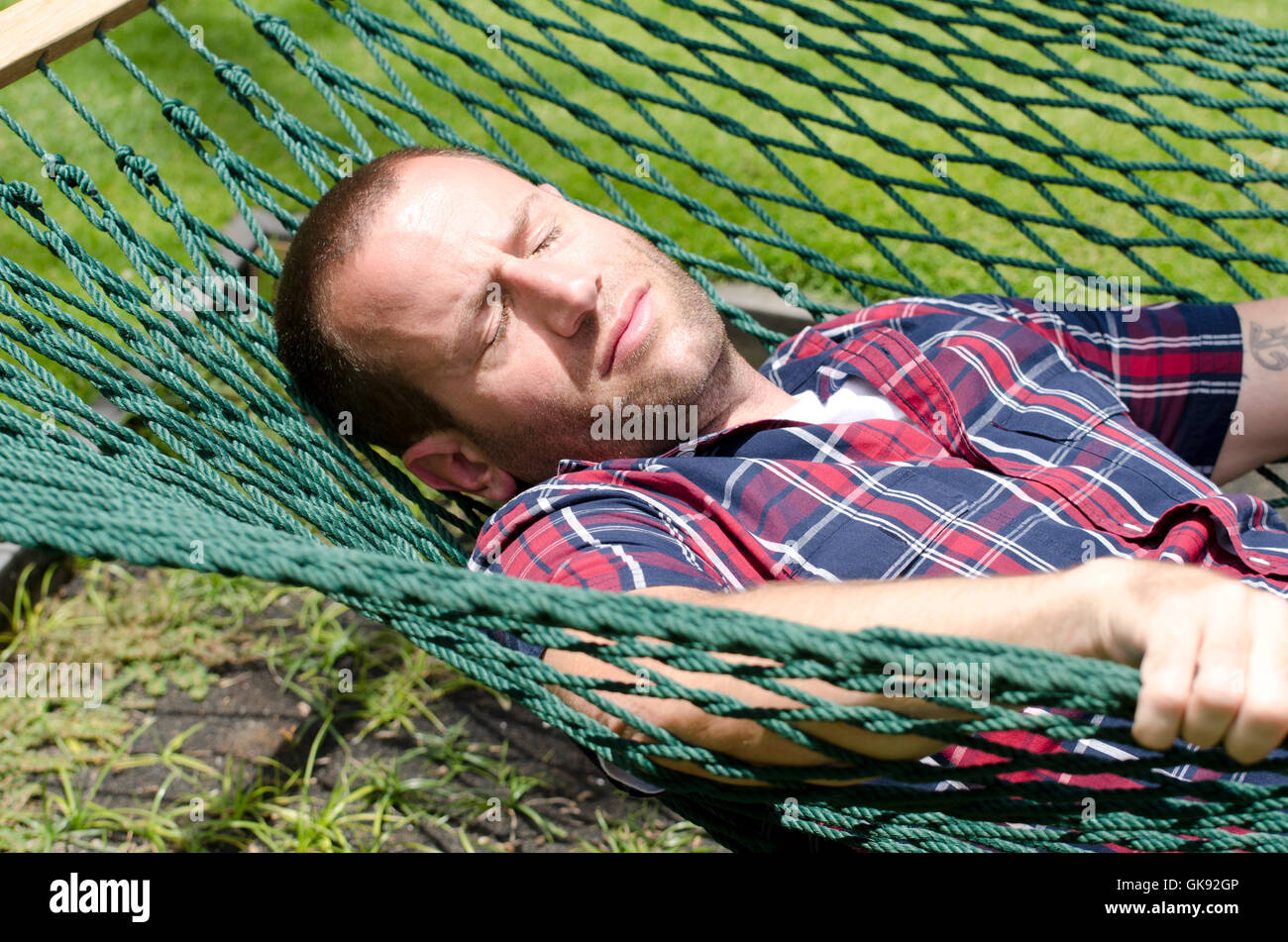 Man sleeping in hammock with eyes closed and arms crossed. Stock Photo