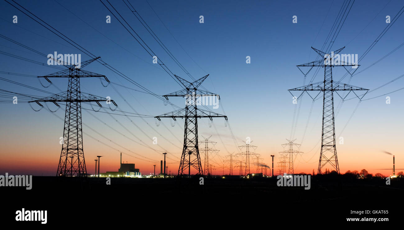 electricity pylons at dusk,on the horizon nuclear power plant Stock Photo
