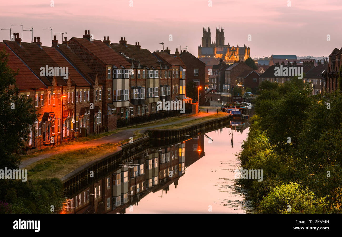 The Minster just after sunset with view of the beck (canal) flanked by modern town houses and barges with reflections. Stock Photo