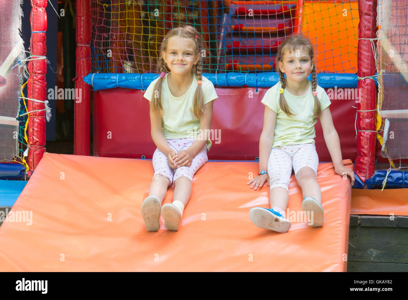 Two girls naprygalis soft children's play room and sat down to rest Stock Photo