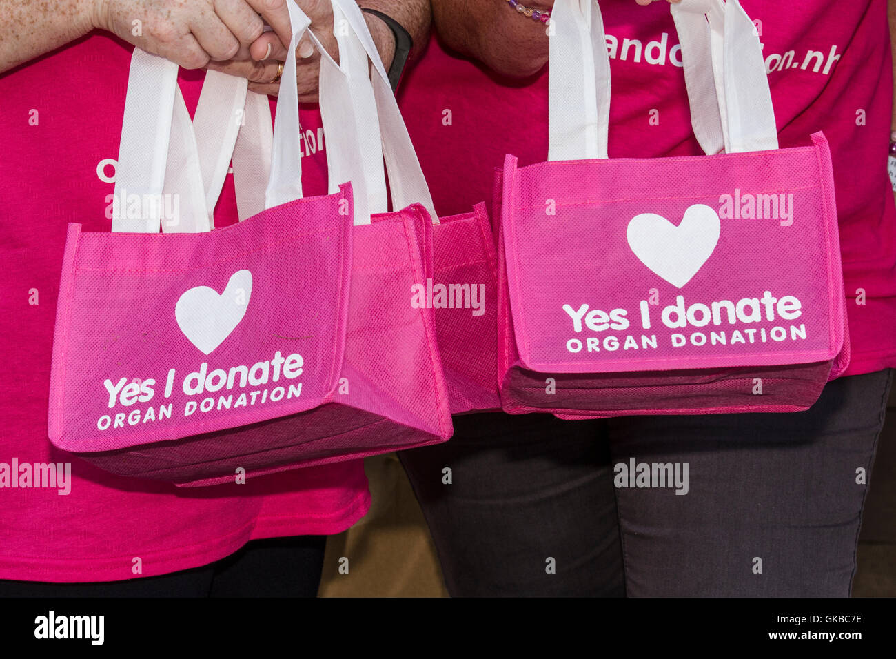 'Yes I donate' pink bags. Young Evie Pownall, girl 6 years old carrying reusable pink bag recommending registering for organ donation, Southport, UK Stock Photo