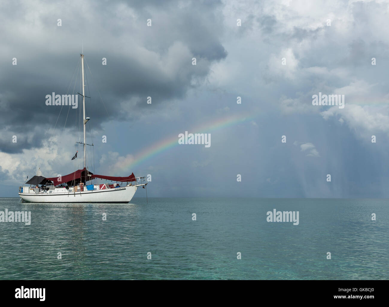 Sailboat floating in the Atlantic Ocean with a rainbow behind it Stock Photo