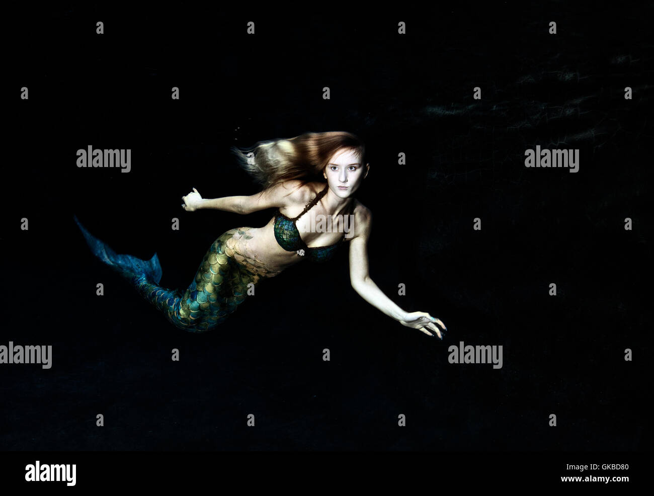 Mermaid swimming in dark water Stock Photo