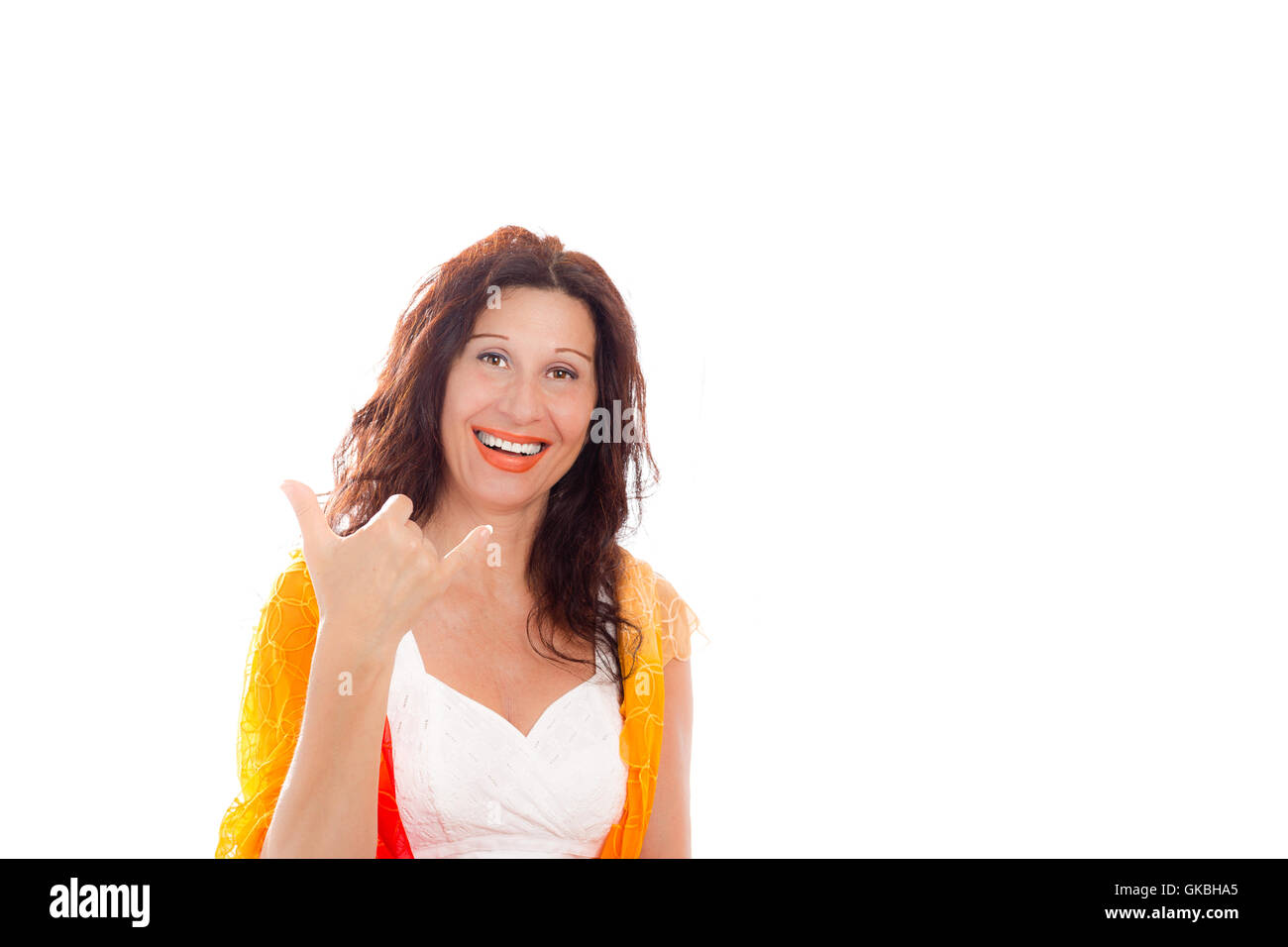 Portrait of gorgeous mature Caucasian woman with Arab and Middle Eastern features smiling and showing Hawaiian Shaka hand sign as satisfaction or welcoming greeting while wearing shawl on shoulders isolated on white background Stock Photo