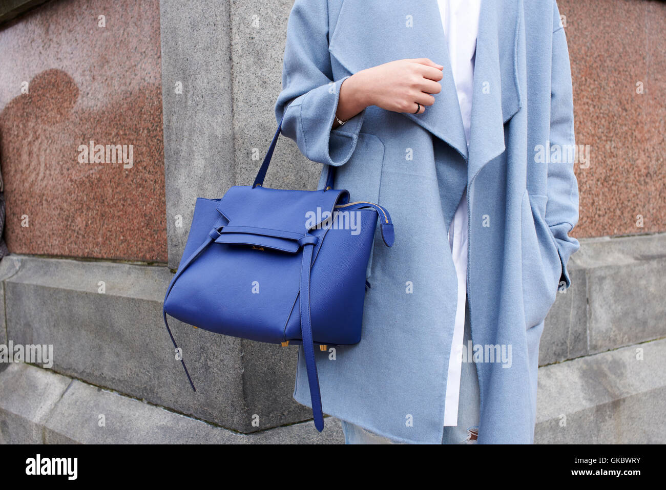 Woman in blue coat holding blue bag, mid section crop Stock Photo