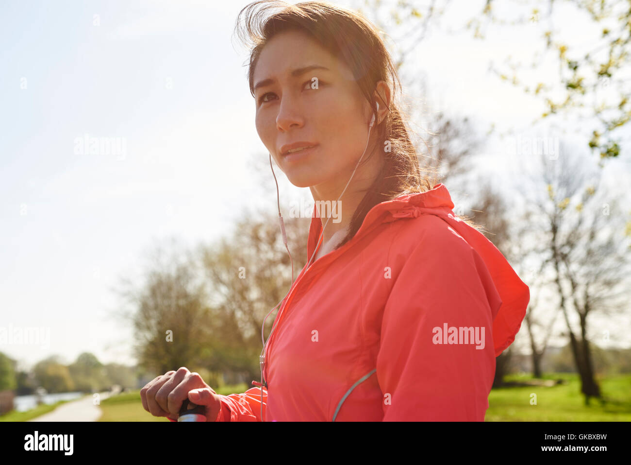 Backlit Portrait Of Young Woman Wearing Earphones Exercising Stock Photo