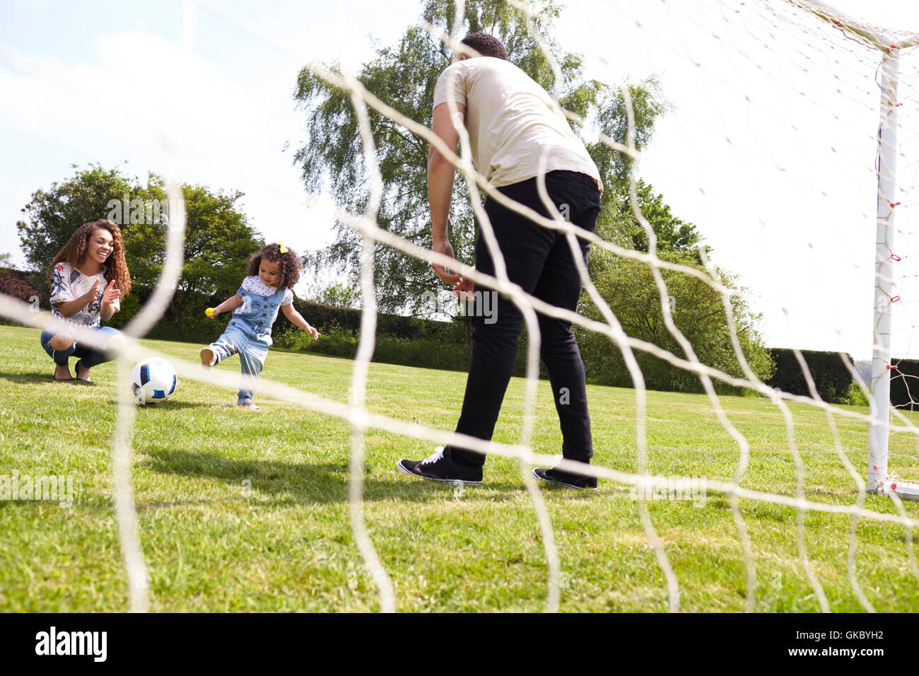 Young girl playing football with her parents, low angle view Stock Photo