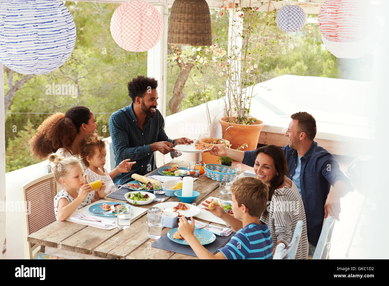 Families Enjoying Outdoor Meal On Terrace Together Stock Photo
