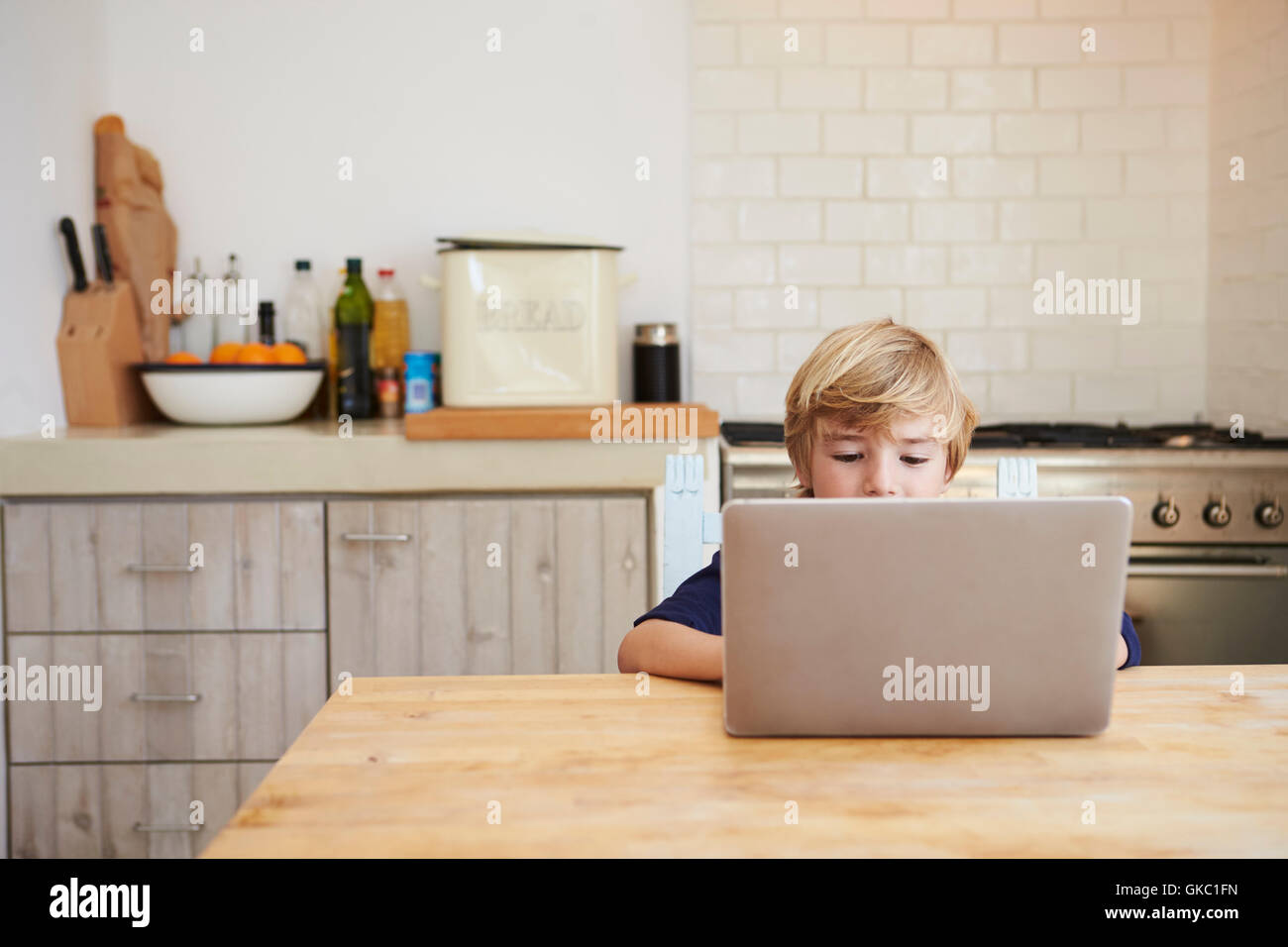 Young boy using laptop computer at kitchen table Stock Photo - Alamy