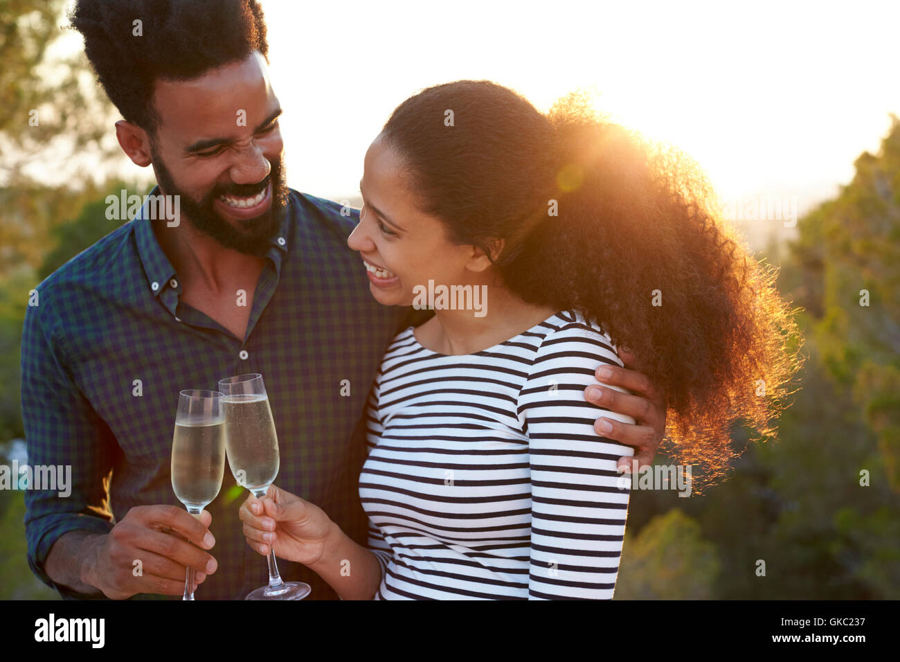 Romantic couple making a toast outdoors, arm around Stock Photo