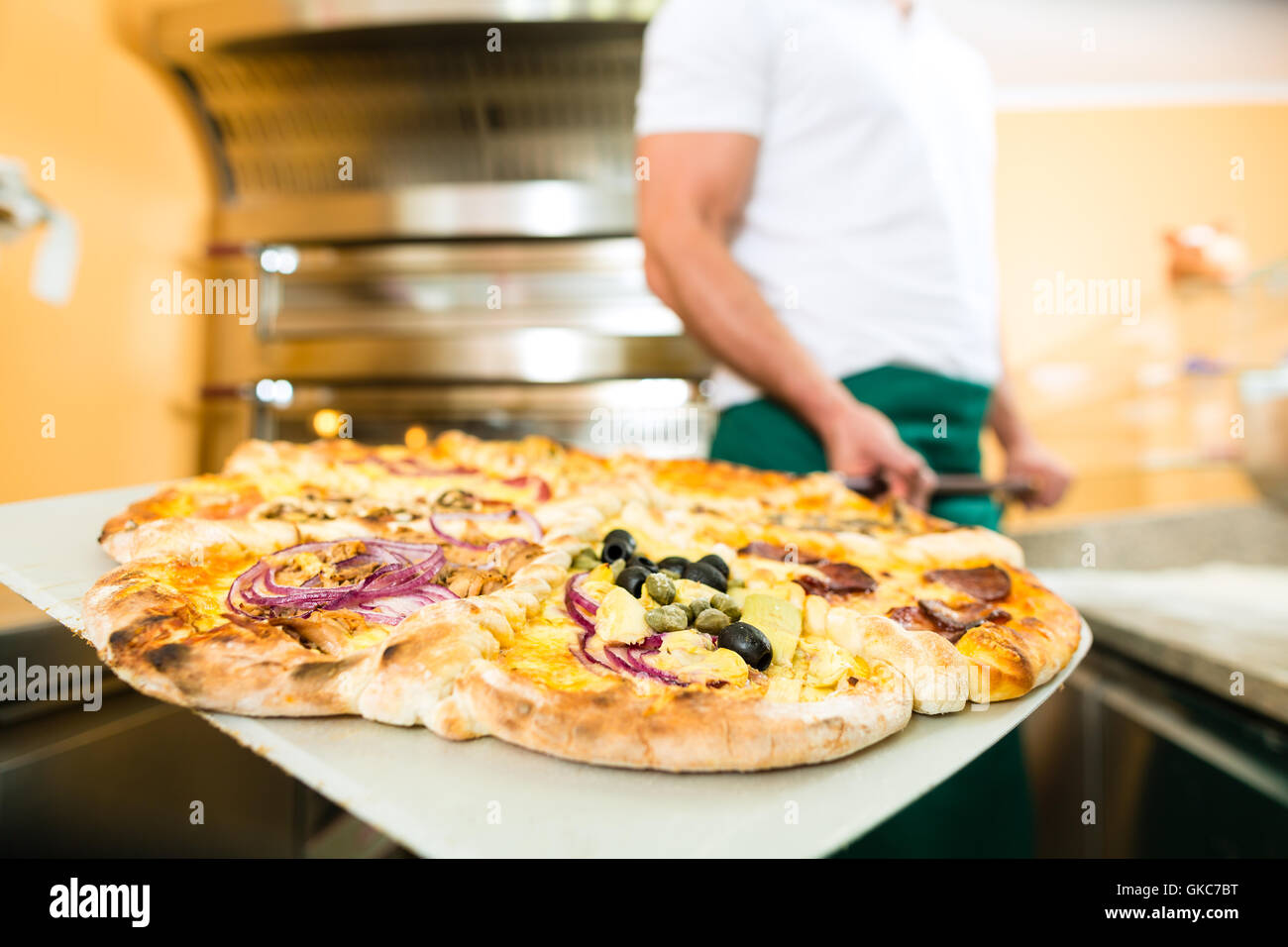 man pushes the finished pizza from the oven Stock Photo
